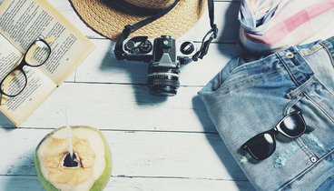 Bild zeigt sommerliche Attribute wie Sonnenbrille, Cocktail, Sommerhose und Buch